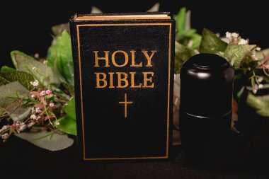 Kutsal İncil ve vazo, siyah arka planda küller, cenaze konsepti.