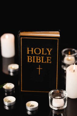 candles and holy bible on black background, funeral concept clipart