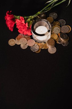 Kırmızı karanfiller, mum ve siyah arkaplanda bozuk paralar, cenaze konsepti