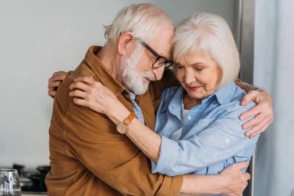 Happy Senior Couple Closed Eyes Hugging Indoors — Stock Photo, Image