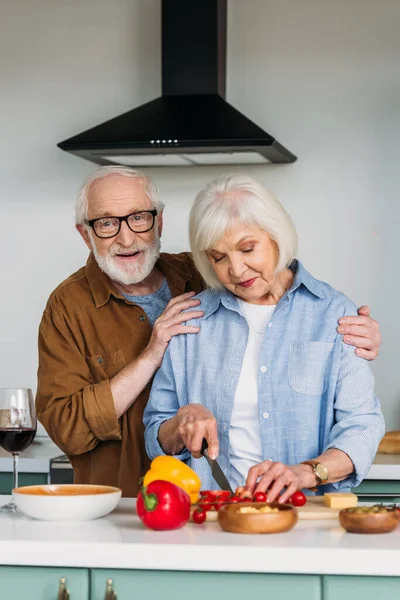 Sorrindo Marido Idoso Abraçando Esposa Cozinhar Jantar Perto Mesa Com — Fotografia de Stock