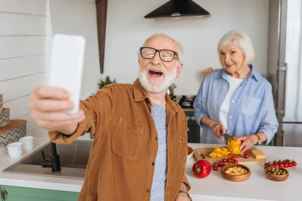 Happy Elderly Husband Taking Selfie Wife Cooking Dinner Kitchen Blurred — Stock Photo, Image