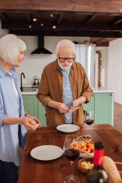 Leende Senior Fru Tittar Man Serverar Bord Med Gafflar Köket — Stockfoto