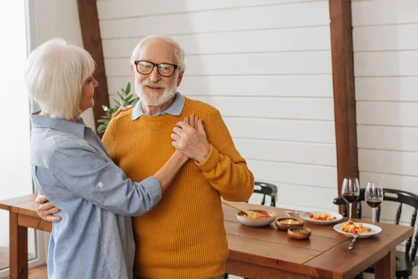 Smiling Senior Husband Looking Camera While Dancing Wife Kitchen Blurred — Stock Photo, Image