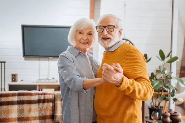 Happy Elderly Couple Looking Camera While Dancing Home Blurred Background — Stock Photo, Image