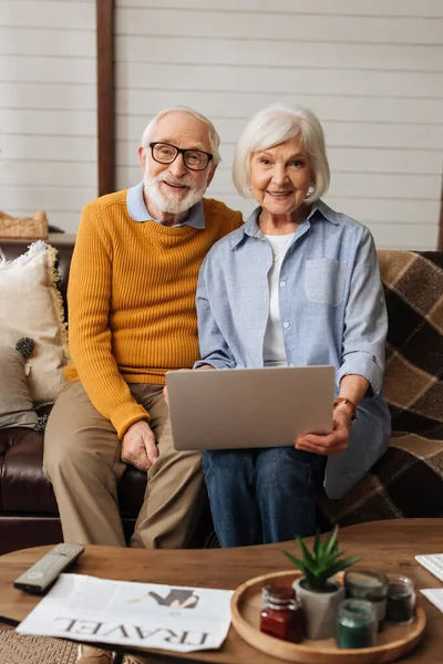 Feliz Casal Idosos Com Laptop Olhando Para Câmera Sofá Primeiro — Fotografia de Stock