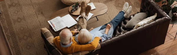 Hoge Hoek Uitzicht Oudere Paar Kijken Terwijl Knuffelen Bank Woonkamer — Stockfoto