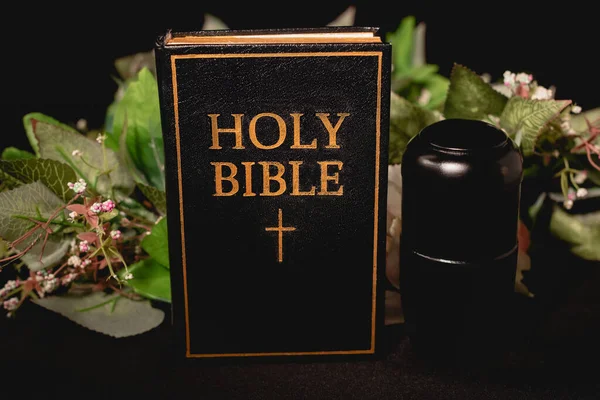 Svatá Bible Urna Popelem Černém Pozadí Pohřební Koncept — Stock fotografie