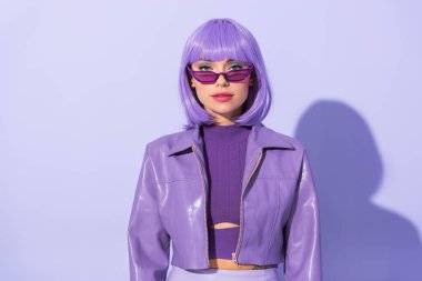 Menekşe renkli arka planda bebek gibi giyinmiş genç bir kadın.