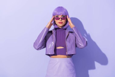 Menekşe renkli arka planda bebek gibi giyinmiş genç bir kadın.