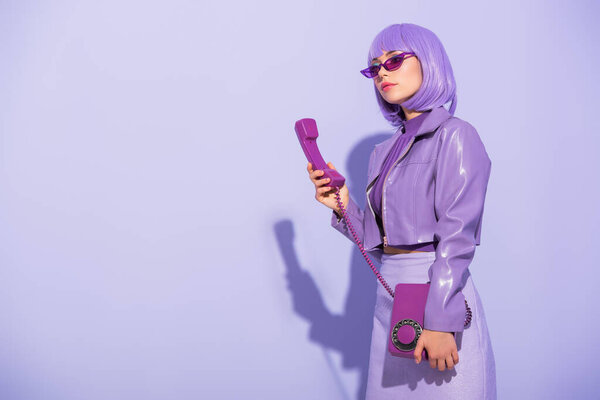 young woman dressed in doll style with retro telephone on violet colorful background