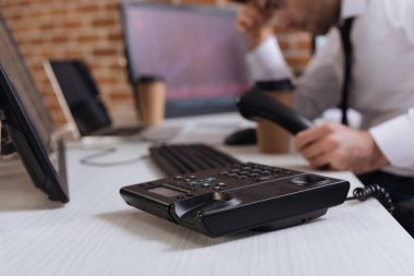 İş adamı yakınındaki masada telefon görüntüsü ve bulanık arka planda bilgisayarlar. 
