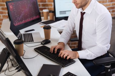 Kahve ve defter yanında bilgisayar kullanan işadamının görüntüsü bulanık önplanda 
