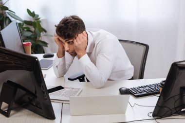 Akıllı telefon ve gazetelerin yanındaki bilgisayara bakarken finans derslerini kontrol eden odaklı işadamı 