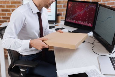 Ofiste bilgisayarların yanında pizza kutusu tutan işadamlarının görüntüsü bulanık. 