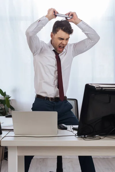 Loco Hombre Negocios Gritando Mientras Sostiene Cuaderno Cerca Las Computadoras — Foto de Stock