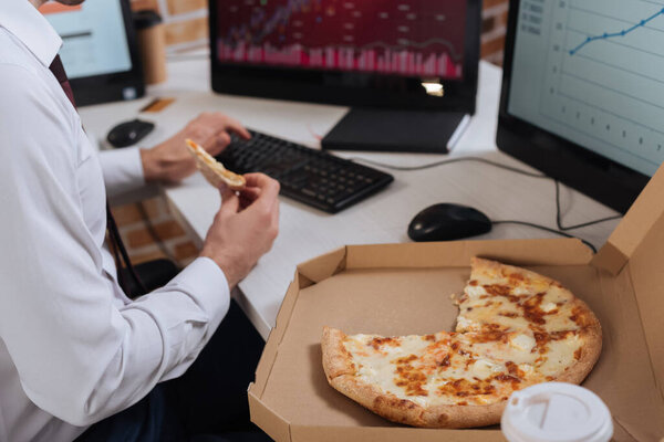 Cropped view of tasty pizza in box near businessman using computer on blurred background 