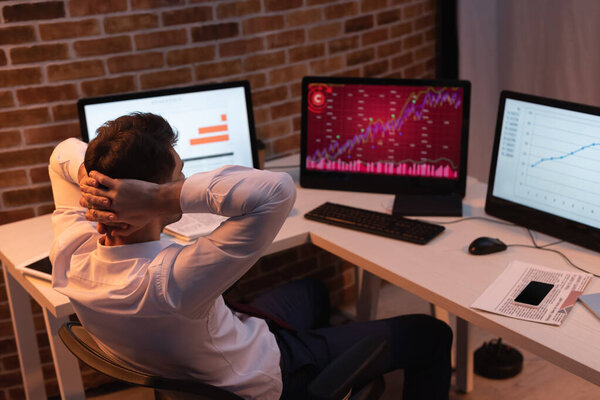 businessman sitting near computers, newspaper and smartphone on blurred background 