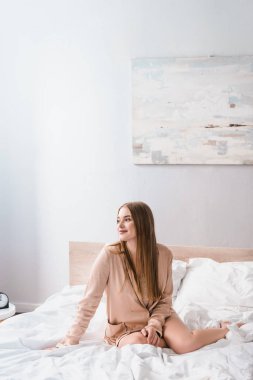 Modern bir yatak odasında yatarken gözlerini kaçıran genç bir kadın. 