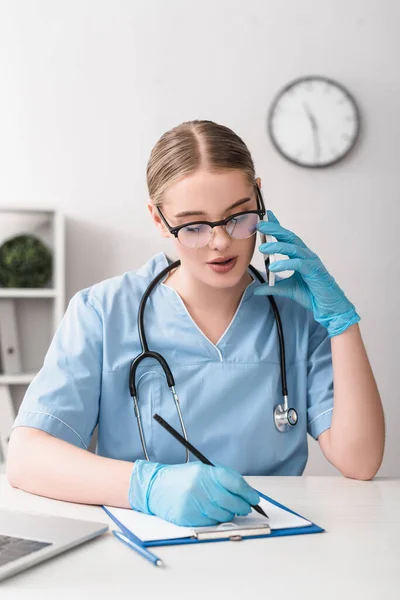 Jovem Veterinário Óculos Luvas Látex Falando Smartphone Perto Laptop Mesa — Fotografia de Stock