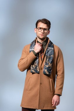 trendy man in glasses and winter coat standing on grey clipart