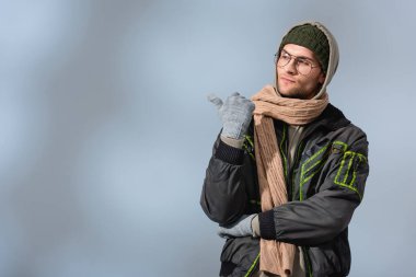 Şapkalı, kapüşonlu ve anorak genç şık adam griyi işaret ediyor.