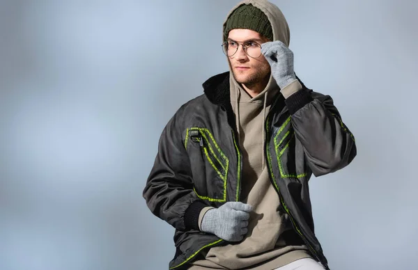 Young Trendy Man Hat Gloves Anorak Adjusting Glasses Grey — Stock Photo, Image