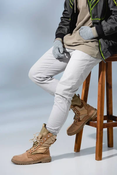 Cropped View Young Trendy Man Hat Anorak Sitting Wooden Stool — Stock Photo, Image