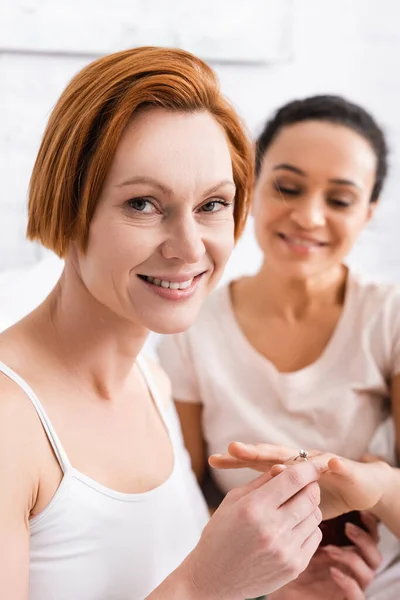 Happy Redhead Woman Looking Camera While Putting Wedding Ring Finger — Stock Photo, Image