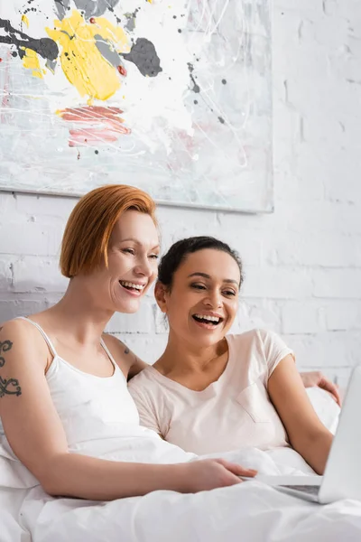 Excited Interracial Lesbian Couple Laughing While Watching Film Laptop Bed — Stock Photo, Image
