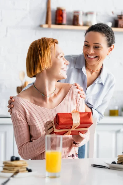 Sonriente Mujer Afroamericana Abrazando Hombros Feliz Novia Lesbiana Sosteniendo Presente — Foto de Stock