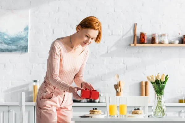 Pelirroja Elegante Mujer Celebración Regalo San Valentín Cerca Mesa Con — Foto de Stock