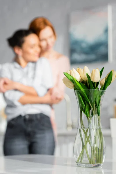 Selective Focus Tulips Vase Interracial Lesbian Couple Hugging Blurred Background — Stock Photo, Image