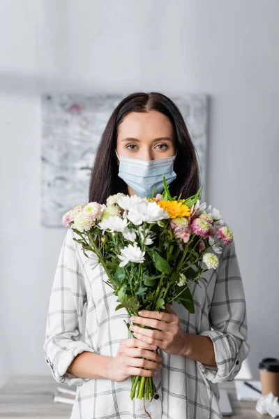 花を持ちながらカメラを見る医療用マスクのアレルギー女性 — ストック写真