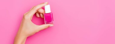 Pembe arka planda bir şişe tırnak minesi tutan kadının kısmi görüntüsü, afiş