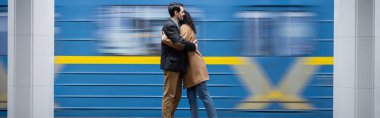 motion blur of interactional couple hugging near wagon in subway, banner clipart