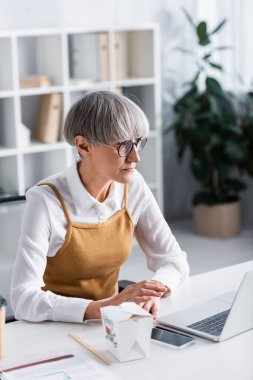 Olgun takım lideri ekipmanların yanında ve karton kutuda yemek servisi yapıyor.