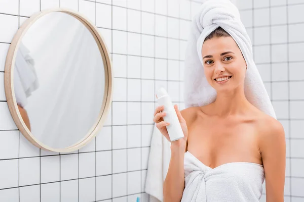 一个快乐的女人在靠近镜子的浴室里拿着除臭剂 看着相机 — 图库照片