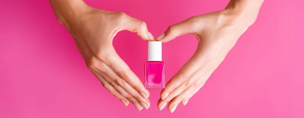 女性手持粉红底色指甲油瓶 横幅手绘心脏标志的局部图像 — 图库照片