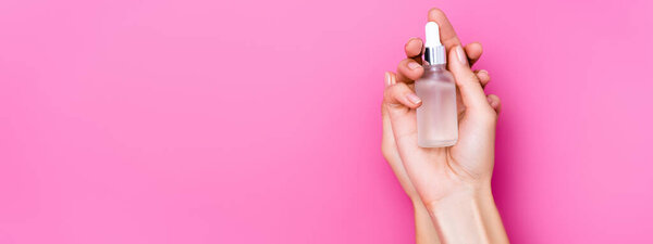 верхний вид ухоженных женских рук с флаконом для удаления кутикулы на розовом фоне, баннер