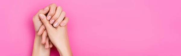 ピンクを背景にパステルマニキュアで女性の手のトップビュー バナー — ストック写真