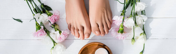 верхний вид гвоздики и цветов эустомы возле ухоженных женских ног и свечи на белой деревянной поверхности, баннер