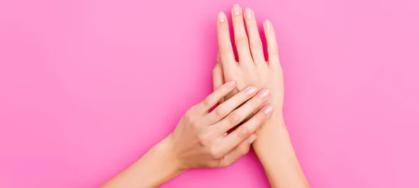 女性の手の上からピンクの背景の爪にパステルカラーのネイルポリッシュ バナー — ストック写真