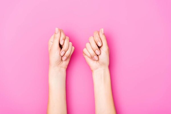 вид женских рук с пастельным лаком для ногтей на ногтях на розовом фоне