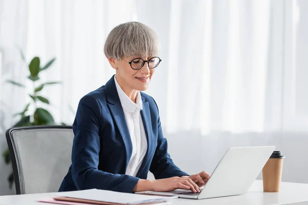 Munter Teamleder Briller Smiler Mens Han Bruker Laptop Nær Drikke – stockfoto