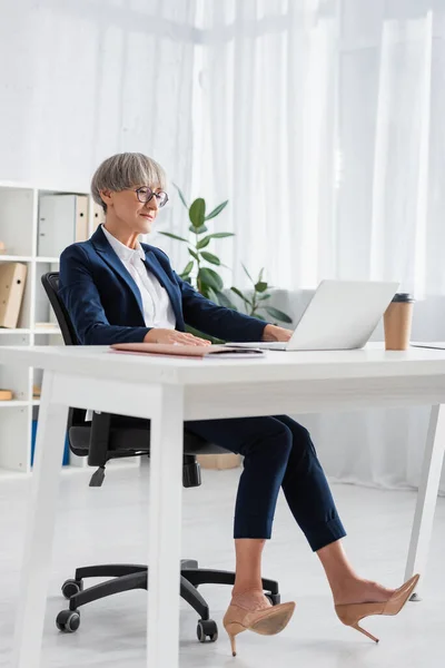 Teamleiter Mittleren Alters Mit Brille Blickt Auf Laptop Auf Tisch — Stockfoto