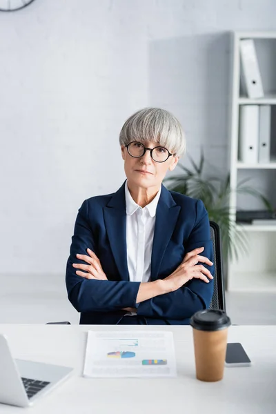 Middle Aged Businesswoman Glasses Sitting Crossed Arms Charts Graphs Desk — Stock Photo, Image