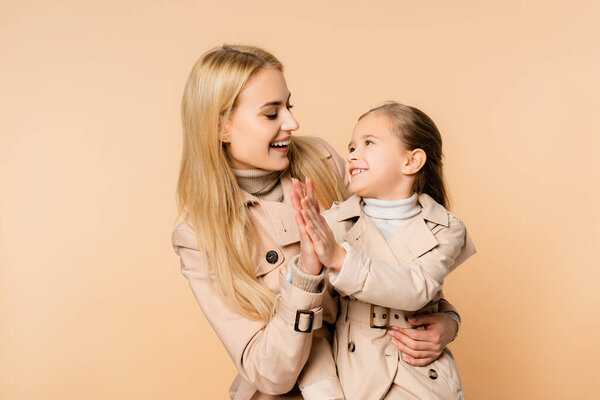 cheerful blonde mother and smiling daughter giving high five isolated on beige