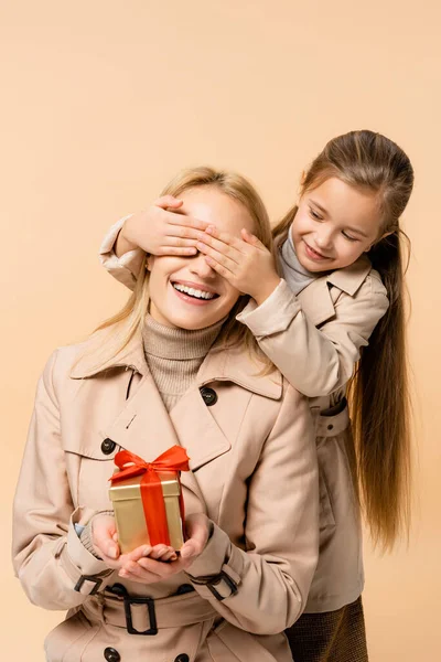 Niño Cubriendo Los Ojos Feliz Madre Con Presente Aislado Beige — Foto de Stock