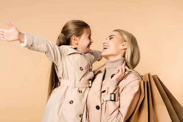 Smiling Mother Holding Paper Bags Looking Daughter Isolated Beige — Stock Photo, Image